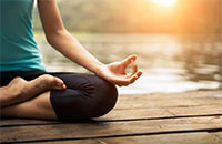 yoga seated pose by calm water and setting sun